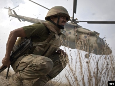 A soldier crouches as an army helicopter takes off on top of Kund mountain near Kotkai village in South Waziristan on October 29.