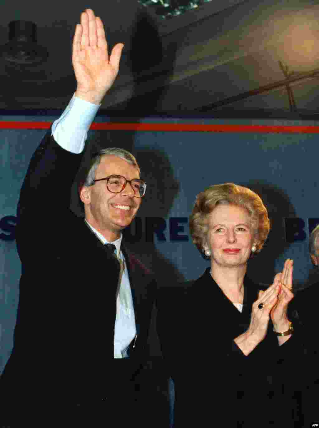 Margaret Thatcher applauds as her successor, John Major, waves in London in March 1992.