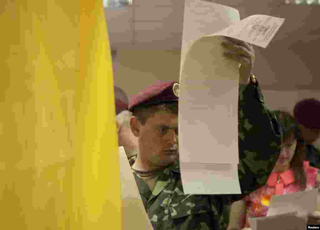 A Ukrainian soldier studies his ballot paper before voting in Kyiv.