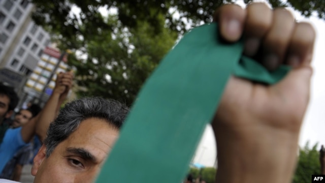 A supporter of Iranian presidential candidate Mir Hossein Musavi waves a green ribbon -- Musavi's campaign color -- during protests in Tehran on June 13.