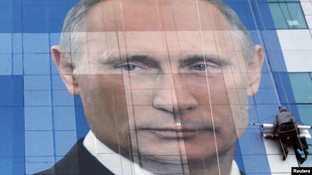 Workers attach an election poster in the southern city of Krasnodar featuring Prime Minister Vladimir Putin appealing to people to vote for United Russia