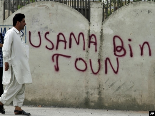 Um homem passa por uma parede com spray-pintada "Osama Bin Town 'sobre ele em Abbottabad em 6 de maio, dias após a operação dos EUA para matar Osama bin Laden.