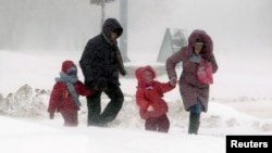 A couple with children walk during a heavy snow storm in central Minsk last week. Despite the fact that spring has now officially arrived, much of the northern hemisphere remains covered in snow.
