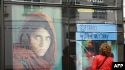 A woman in Paris looks at a poster of the famous photograph of Sharbat Gula.