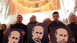 Сербські прихильники Володимира Путіна стоять з його портретами у церкві в Бєлграді