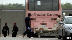 Pakistani security officials stand beside a bus that was attacked while carrying members of Ismaili Shia community, outside a local hospital in Karachi, May 13, 2015