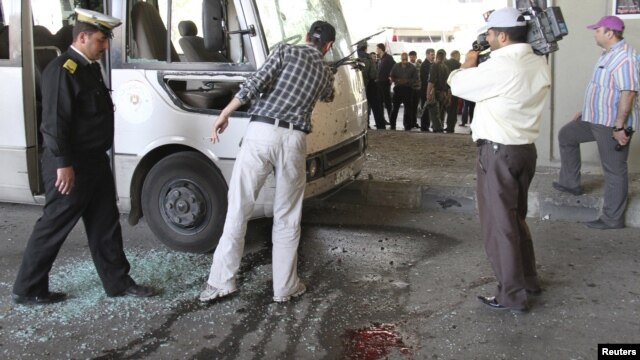 Syrian security personnel inspect the wreckage of a bus, after a bomb exploded in central Damascus on April 27.