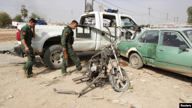 Iraqi security personnel inspect the site of a bomb attack in Kirkuk on October 24, where a child was killed.