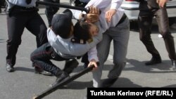 Police and a protester armed with a wooden stick clash in front of the Azerbaijani Education Ministry building in Baku on October 5.