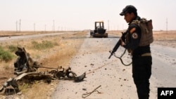 A member of Iraqi government forces inspects a wreckage on the side of a road Qayara Air Base late last month.