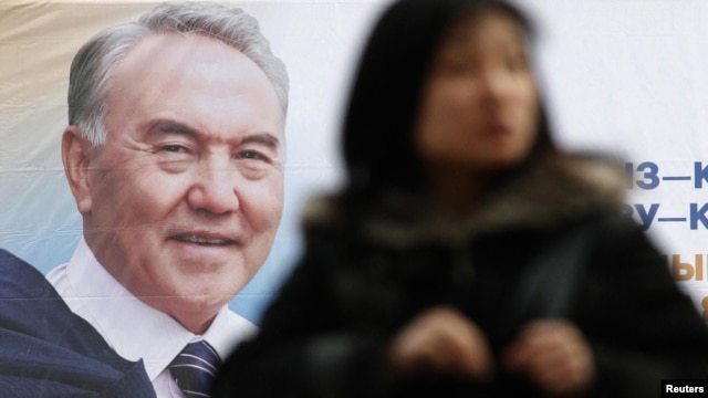 A woman walks past an election poster of Kazakh President Nursultan Nazarbaev in Almaty on February 22.