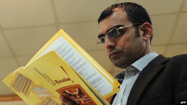 Pakistani investigative journalist Umar Cheema glances at his report prior to addressing a news conference in Islamabad on December 12.