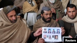 Afghan villagers show a picture of nine men during a protest last month against U.S. Special Forces accused of overseeing torture and killings in Wardak Province.