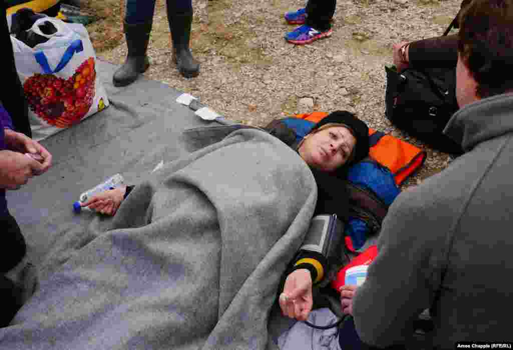An unidentified migrant woman, who is pregnant, is treated by medical personnel after arriving on the Greek island Lesbos on February 26.