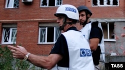 OSCE observers inspect a site near residential buildings damaged by recent shelling in Donetsk, eastern Ukraine.