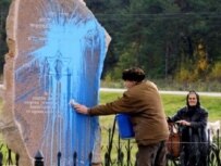 A Belarusian man cleans a vandalized Holocaust memorial in the town of Lida (AFP)