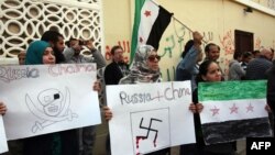 Syrians living in Libya wave the former Syrian flag and hold anti-Russia and -China placards as they protest outside Moscow's embassy in Tripoli on February 5.