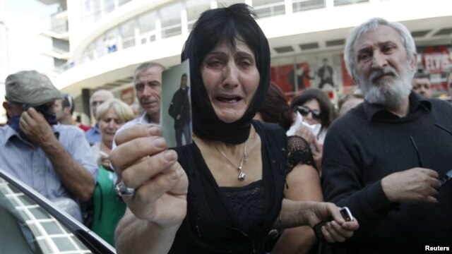 A woman holds a picture of her son, whom she says became an invalid from injuries sustained while in prison, during a protest rally in Tbilisi on September 19.