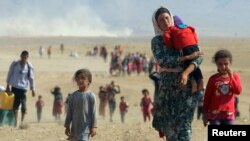 Displaced people from the minority Yazidi sect, fleeing violence from forces loyal to the Islamic State in Sinjar town, walk toward the Syrian border, on the outskirts of Sinjar Mountain, earlier this week.