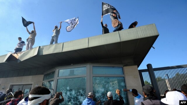 Tunisian protesters break windows as they hold Islamic flags above the gate of the U.S. Embassy compound in Tunis during a protest against the film on September 14.