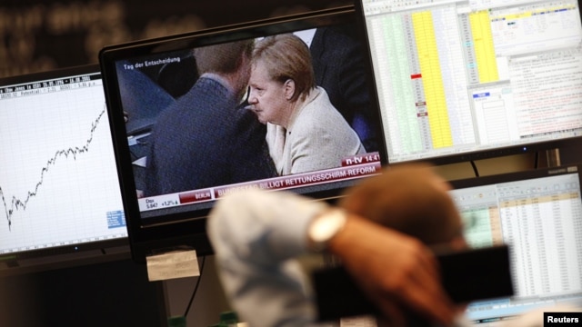 A trader at the Frankfurt stock exchange watches a news broadcast showing German Chancellor Angela Merkel. (file photo)