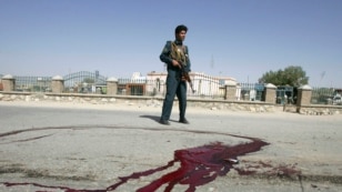 A police officer stands guard near bloodstains on the ground at the site of the bomb blast in Ghazni Province.