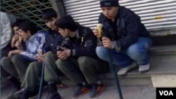 Young members of the Basij militia display their truncheons as they sit streetside and eat ice cream in an undated photo from Iran.