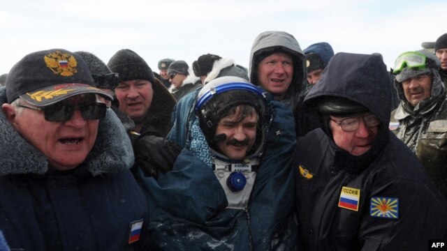 Ailing? Russian space agency rescuers help cosmonaut Aleksandr Kaleri shortly after his landing near the town of Arkalyk, in Kazakhstan on March 16.