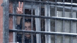Belarus -- A detainee arrested in protests gestures from a prison cell at a detention center in Minsk, 29Dec2010.