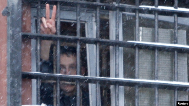 Belarus -- A detainee arrested in protests gestures from a prison cell at a detention center in Minsk, 29Dec2010.