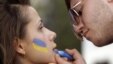A man paints the colours of the Ukrainian national flag on a woman