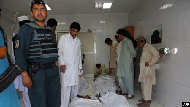 Police and civilians gather at a hospital morgue holding the bodies of suicide-bombing victims in Khost on June 20.