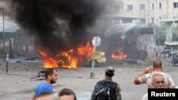 A Syrian Army soldier and civilians inspect the damage after a number of explosions hit the Mediterranean port of Tartus on May 23.