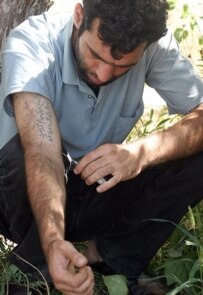 A drug addict shoots up in a Tehran park (Fars file photo)