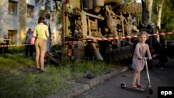 A girl plays in front of a destroyed truck used by pro-Russian militants, which was bombed by Ukrainian Army soldiers during clashes in Donetsk on May 27.