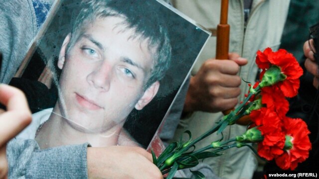 A mourner in Minsk holds a photograph of Ihar Ptsichkin, who died in prison under mysterious circumstances.