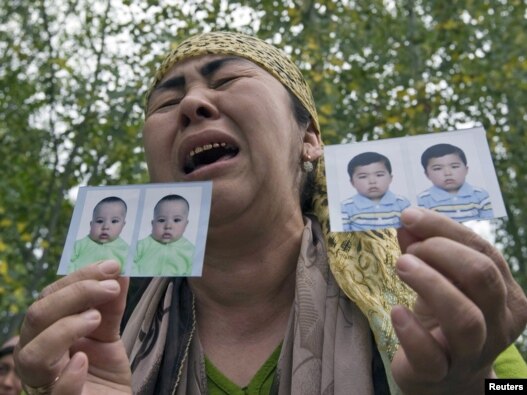 An ethnic Uzbek refugee shows photos of her missing grandsons as she stands on the Kyrgyz-Uzbek border, near the village of Yorkishlak, on June 15.