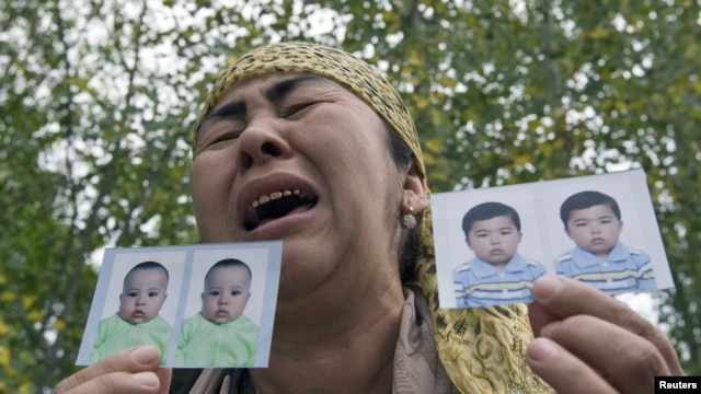 An ethnic Uzbek refugee shows photos of her missing grandsons as she stands on the Kyrgyz-Uzbek border on June 15.