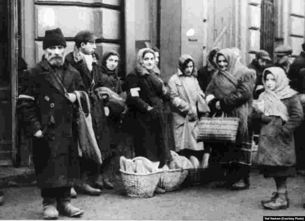 Jews stand by bread baskets on a ghetto street.