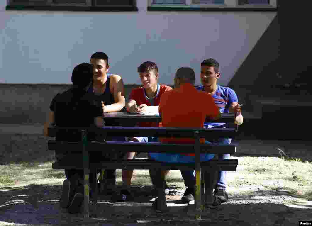 Syrian asylum seekers sit and talk outside the Bogovadja center.