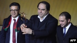 The president of Afghanistan's soccer federation, Karim Keramuddin (center), holds up the 2013 FIFA Fair Play Award in Zurich on January 13.