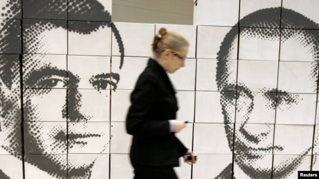 A woman walks by a panel made of cardboard boxes, displaying President Dmitry Medvedev (left) and Prime Minister Vladimir Putin in Rostov na Donu, 21Oct2010