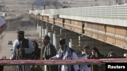 Afghans cross a border bridge over the Pyanj River into the Tajik town of Lower Pyanj, 26Aug2007