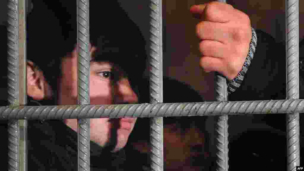 A detained illegal migrant from Uzbekistan stands behind the bars of his jail cell at the Kazan railway station in Moscow on January 24. Police detained about 30 illegal migrants during a routine check at the station. In an article published earlier on his campaign website, Russian Prime Minister Vladimir Putin pledged to toughen up immigration legislation. (AFP/Andrey Smirnov)
