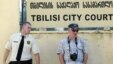Тбилиси сотының алдында тұрған полицей мен фотограф. Көрнекі сурет