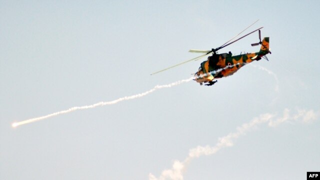 A military attack helicopter fires missiles during Syrian Army maneuvers at an undisclosed location on July 10.