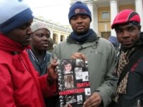 African students hold pictures of foreigners killed in St. Petersburg, including Lamzar Samba and a nine-year-old Tajik girl, Khursheda Sultanova (RFE/RL)
