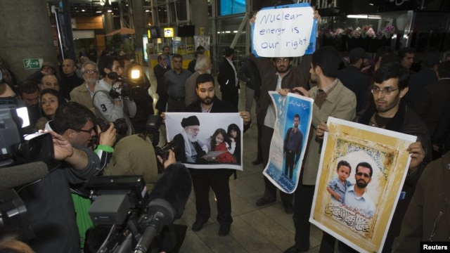 Iranian students hold up pictures of Iranian scientist Mostafa Ahmadi-Roshan, who was killed in a bomb blast on January 11,  as they wait for the arrival of the IAEA delegates at Tehran's Imam Khomeini International Airport on January 29.