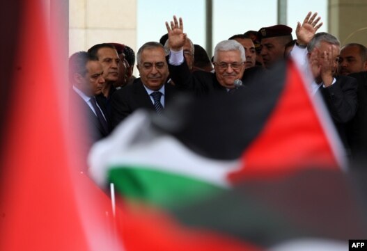 Palestinian president Mahmud Abbas waves to thousands of cheering Palestinians as they welcome their president at his Ramallah headquarters