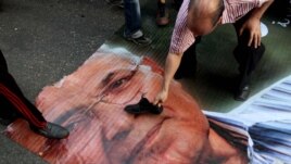 Demonstrant stavlja svoju cipelu na lik Ahmada Šafika